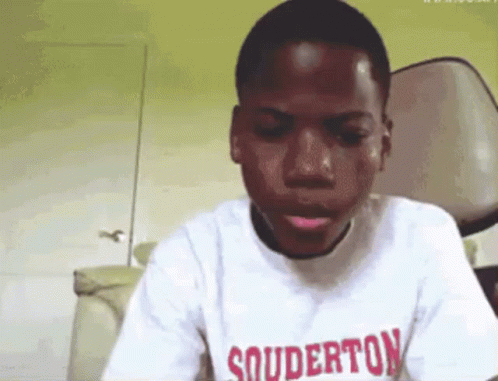 A Young Boy Wearing A White Shirt With Souderton On It GIF