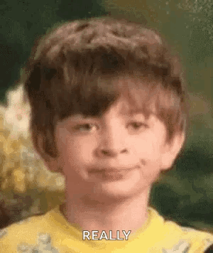 A Young Boy Wearing A Yellow Shirt Is Smiling And Making A Funny Face . GIF