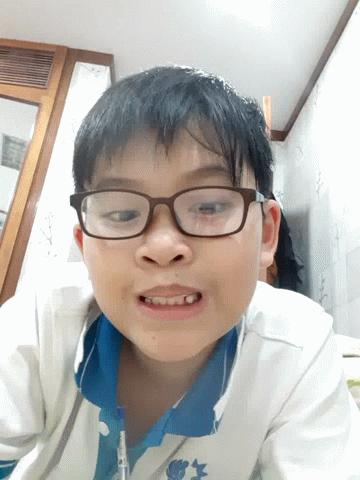 A Young Boy Wearing Glasses And A Blue Shirt Is Smiling For The Camera GIF