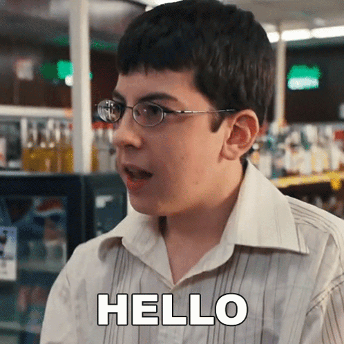 A Young Boy Wearing Glasses And A White Shirt Is Saying Hello GIF