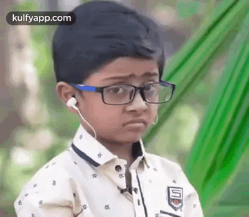 A Young Boy Wearing Glasses And Ear Buds Is Making A Sad Face . GIF