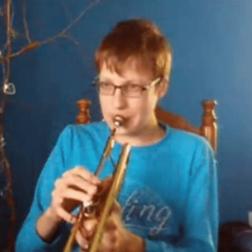 A Young Boy Wearing Glasses Is Playing A Trumpet . GIF