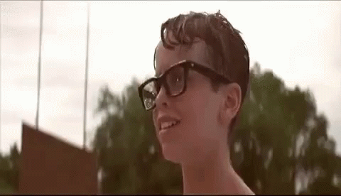A Young Boy Wearing Glasses Is Smiling In Front Of A Field . GIF