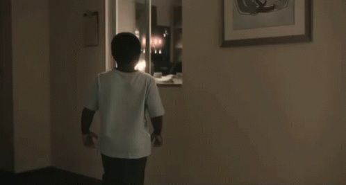 a young boy wearing glasses is standing in a doorway with his mouth open and a surprised look on his face .