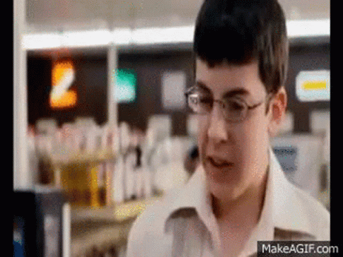 A Young Boy Wearing Glasses Is Standing In A Store Looking At Something . GIF