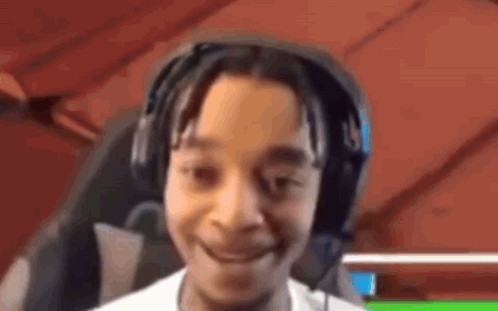 A Young Boy Wearing Headphones Is Smiling And Looking At The Camera . GIF