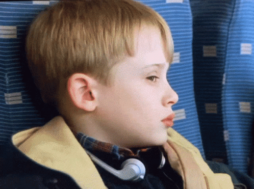 A Young Boy Wearing Headphones Looks To The Side GIF
