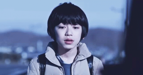 A Young Boy With A Backpack On His Back Is Looking At The Camera . GIF