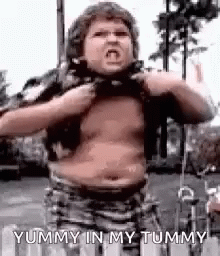 A Young Boy With A Very Fat Belly Is Taking Off His Shirt . GIF
