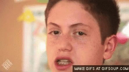 A Young Boy With Braces On His Teeth Is Looking At The Camera . GIF