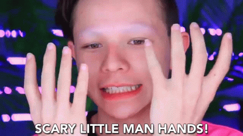 A Young Boy With Makeup On His Face Is Holding His Hands Up In Front Of His Face And Saying Scary Little Man Hands . GIF