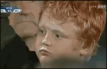 A Young Boy With Red Hair Is Being Kissed By A Man While Watching A Soccer Game . GIF