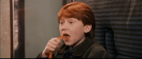 a young boy with red hair is eating a carrot