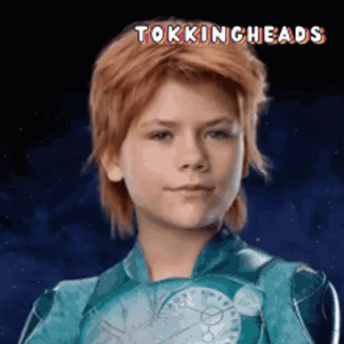 A Young Boy With Red Hair Is Wearing A Blue Suit With The Words Tokingheads Written Above Him GIF