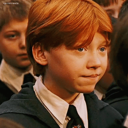 A Young Boy With Red Hair Is Wearing A Suit And Tie And Making A Face . GIF