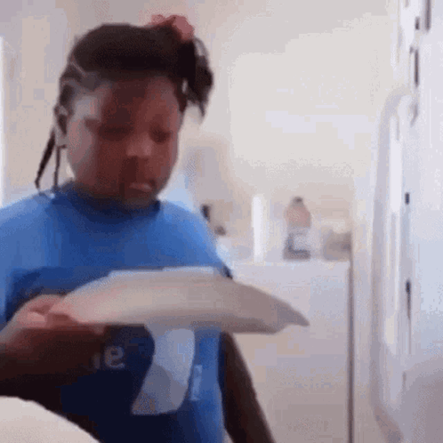 A Young Girl In A Blue Shirt Is Holding A Piece Of Paper In Her Hand . GIF