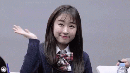A Young Girl In A School Uniform Is Sitting At A Table With A Bottle Of Water . GIF