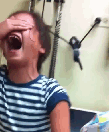 A Young Girl In A Striped Shirt Is Covering Her Face With Her Hand GIF