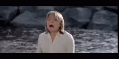 A Young Girl In A White Shirt Is Standing In The Water . GIF