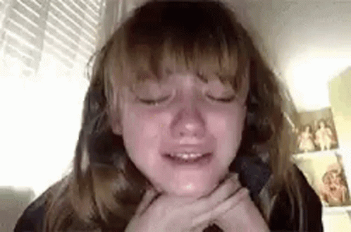 A Young Girl Is Crying While Sitting In A Chair With Her Eyes Closed . GIF