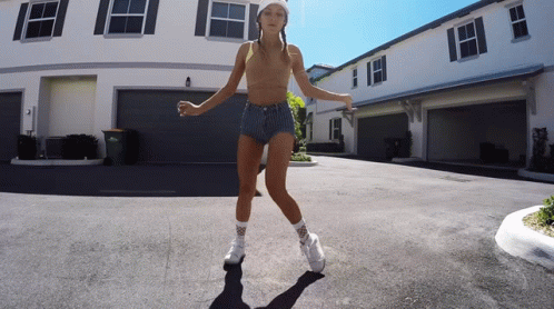 A Young Girl Is Dancing In Front Of A White Building GIF
