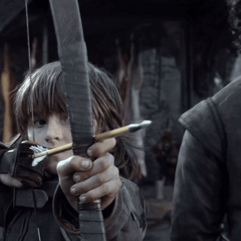A Young Girl Is Holding A Bow And Arrow In Her Hands GIF