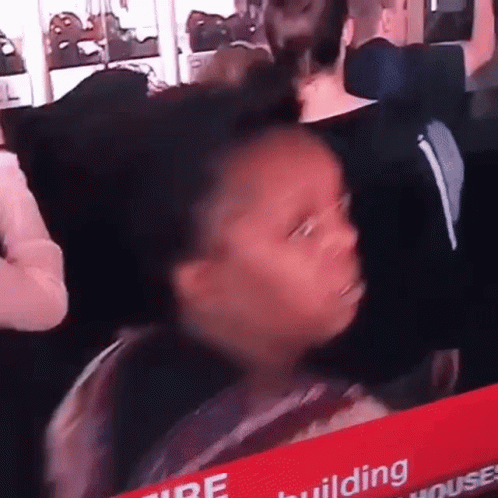 A Young Girl Is Sitting In A Crowd Of People Looking At A Tv Screen . GIF