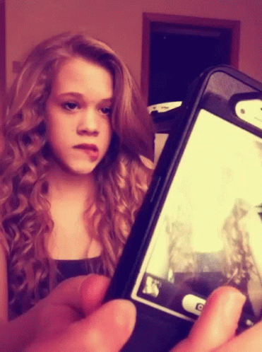 A Young Girl Is Taking A Picture Of Herself On Her Phone GIF
