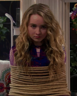 A Young Girl Is Tied Up With A Rope And Looking At The Camera GIF