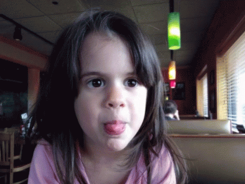 A Young Girl Sticking Her Tongue Out In A Restaurant GIF