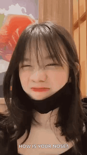 A Young Girl Wearing A Black Mask Is Making A Funny Face . GIF