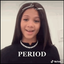 A Young Girl Wearing A Black Shirt And A Necklace Is Smiling . GIF