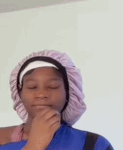 A Young Girl Wearing A Purple Hat And A Blue Shirt Is Looking At The Camera . GIF