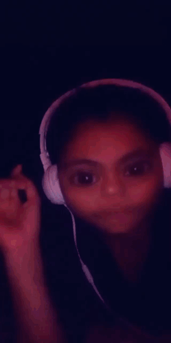 A Young Girl Wearing Headphones Is Smiling And Making A Funny Face GIF