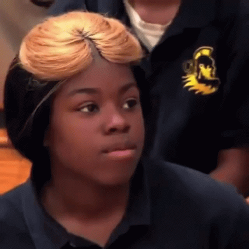 A Young Girl With Blonde Hair Is Making A Funny Face While Wearing A Blue Shirt . GIF