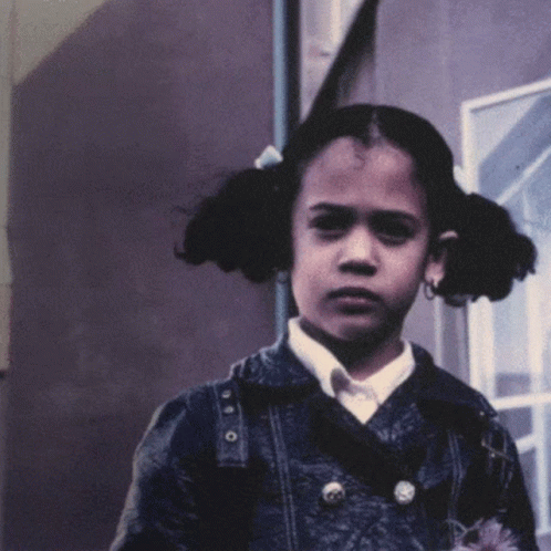 A Young Girl With Pigtails Is Wearing A Denim Jacket And A White Shirt GIF