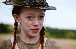 A Young Girl With Pigtails Wearing A Hat And A White Shirt . GIF