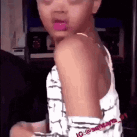 A Young Girl With Pink Lipstick On Her Lips Is Standing In A Room . GIF