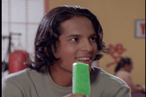 A Young Man Holding A Green Popsicle In His Mouth GIF