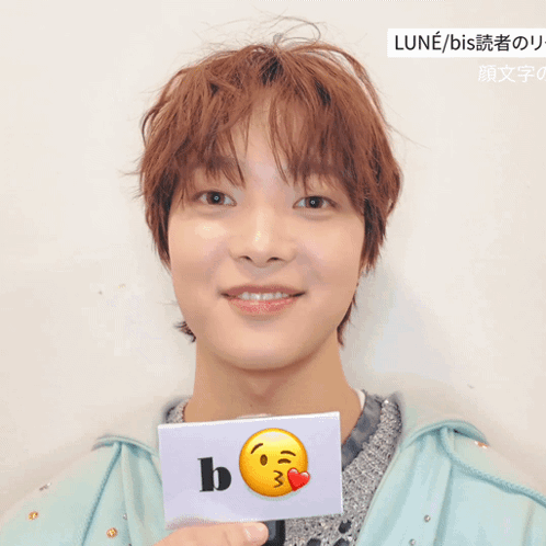A Young Man Holds A Card With A Smiley Face And The Letter B GIF