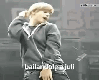 A Young Man In A Black Hoodie Is Dancing On A Stage In Front Of A Crowd . GIF
