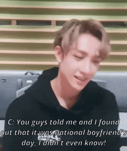 A Young Man In A Black Hoodie Is Sitting In Front Of A Window And Talking . GIF