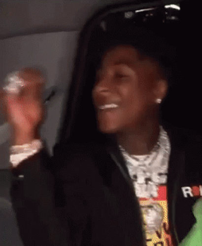 A Young Man In A Black Jacket Is Sitting In A Car And Smiling . GIF