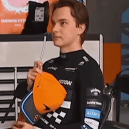 A Young Man In A Black Shirt Is Holding An Orange Hat In His Hands . GIF