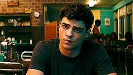 A Young Man In A Black Shirt Is Sitting At A Table In A Restaurant . GIF