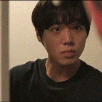 A Young Man In A Black Shirt Looks At Himself In A Mirror GIF