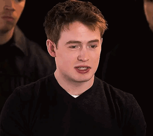 A Young Man In A Black Sweater Is Making A Funny Face . GIF