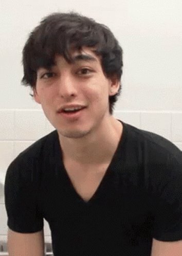 A Young Man In A Black T-Shirt Is Making A Funny Face . GIF