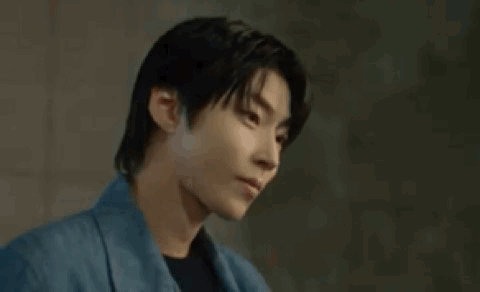 A Young Man In A Blue Jacket Is Looking Down . GIF