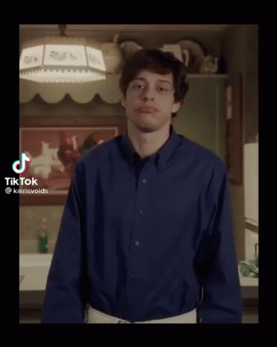 A Young Man In A Blue Shirt Is Standing In A Kitchen With His Arms Outstretched . GIF